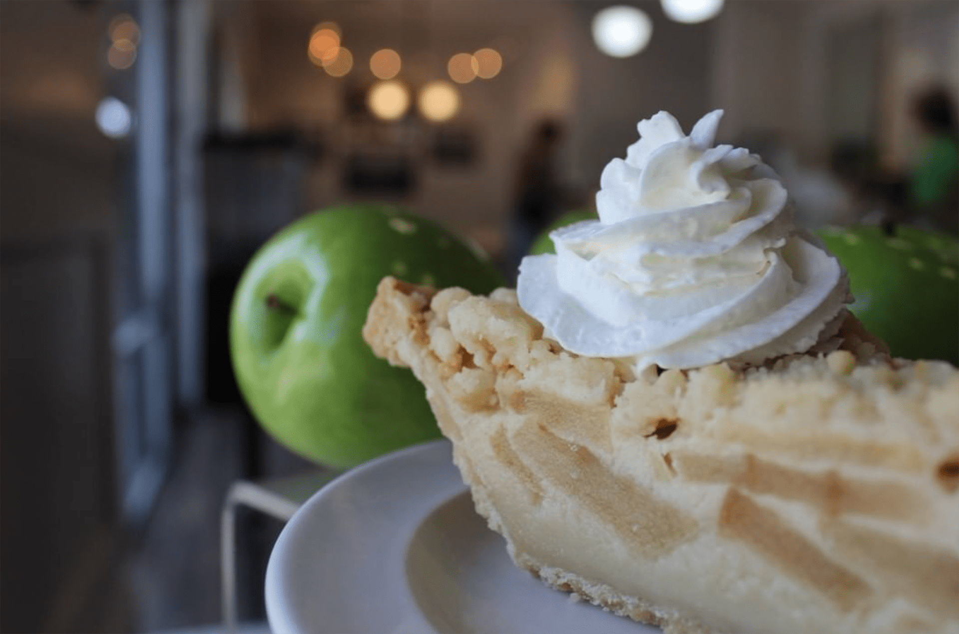 Slice of apple pie topped with whipped cream. 