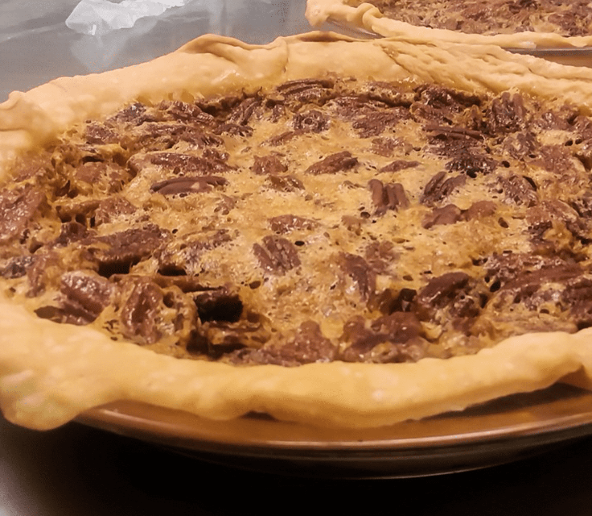 A large pie with crust cooked over the pan. It's covered in peanut butter. 