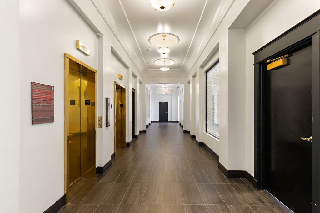 a long hallway featuring gold elevator doors and entrances to private offices 