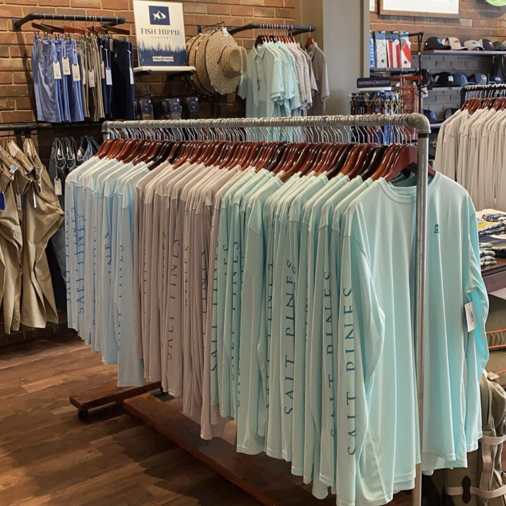 Rack of blue, tan, and teal long sleeved shirts with logos. 