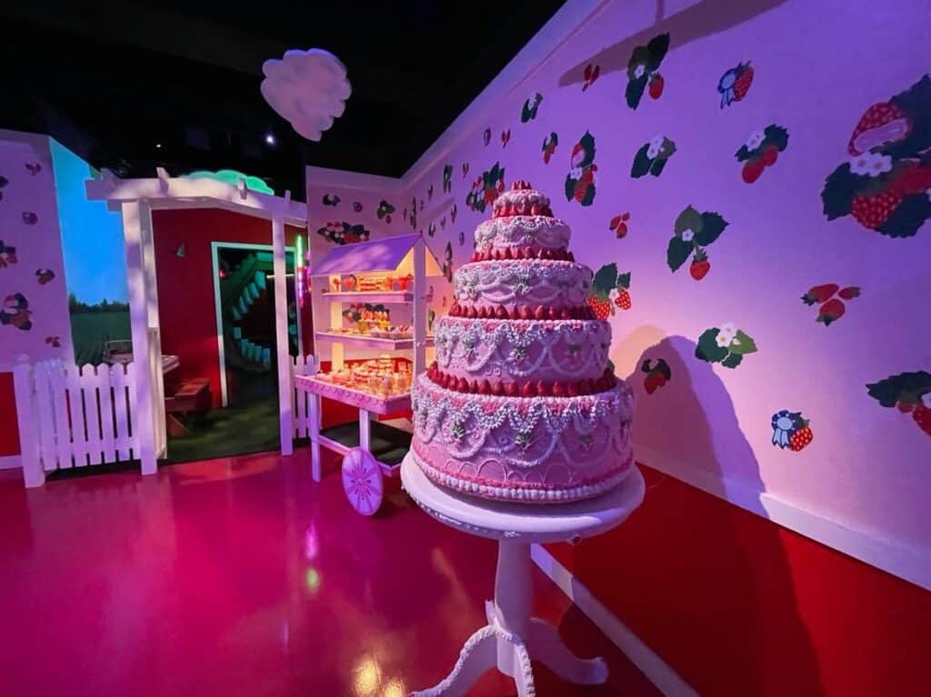 a 5-tier pink cake in an all pink rom with strawberry stickers on the wall