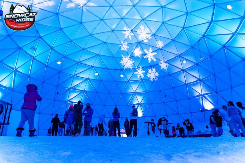 inside a geodesic dome with real snow on the ground and blue lights. 