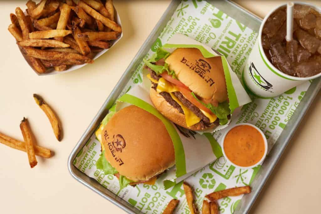 a photo of two cheeseburgers on a tray with a said and French fries