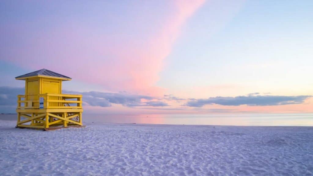 A sunset beach view with a yellow lifeguard tower