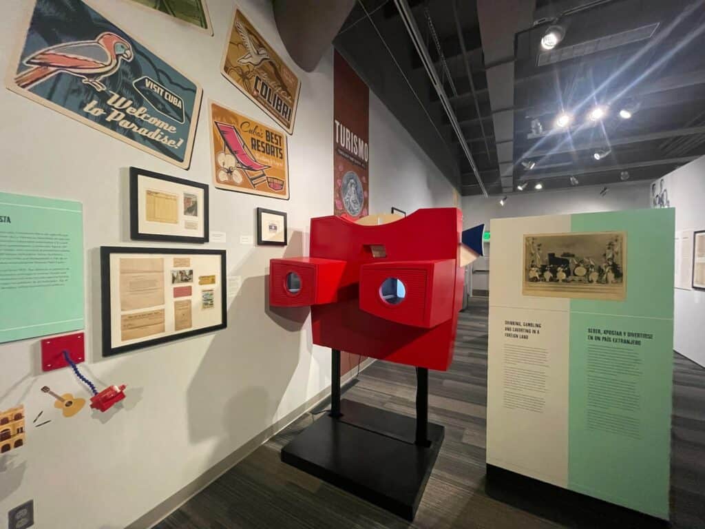Large red vision finder next to a display of old postcards inside a gallery space