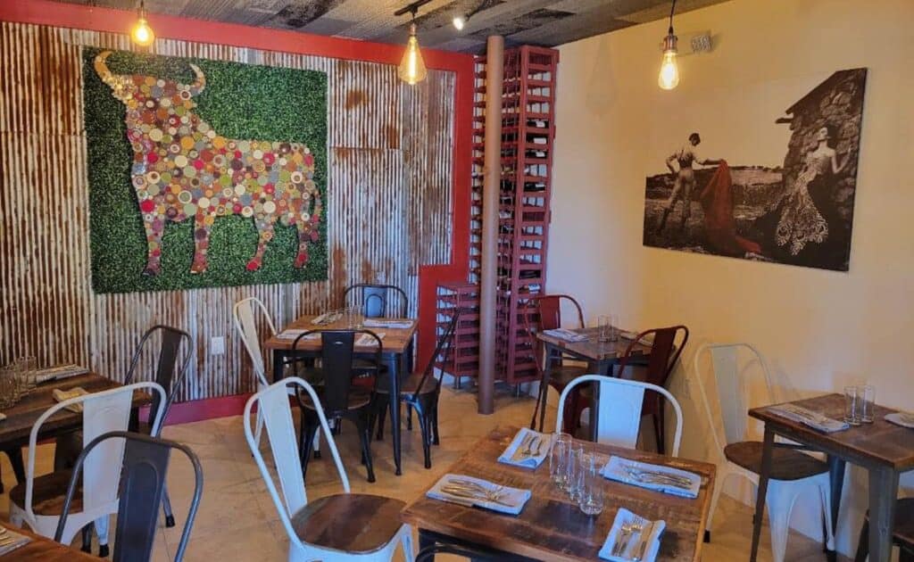 inside a restaurant with sheet metal walls, a black and white photo on the wall, and a block of ivy. 