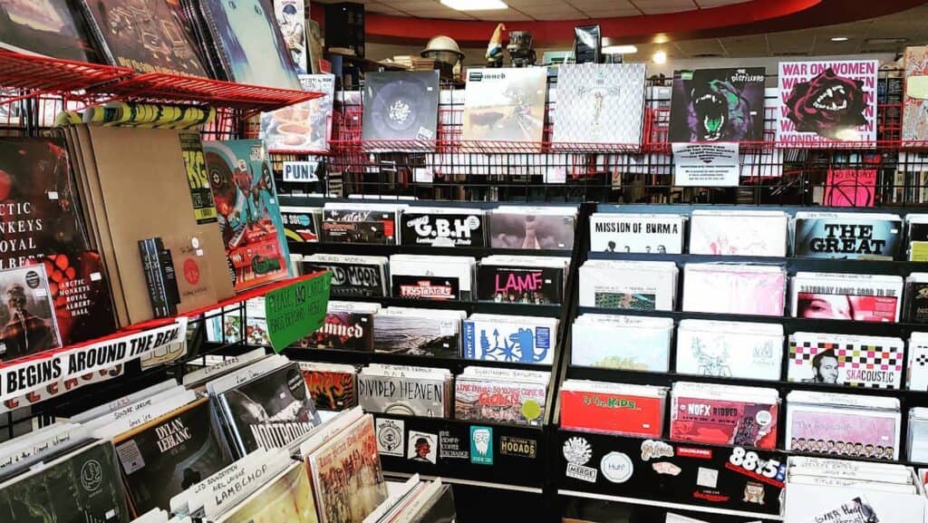 Inside of a record store with book and vinyl records displayed on tiers of shelves.