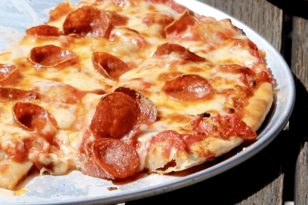 A cheese pizza topped with pepperoni. The slices are cut into squares. 