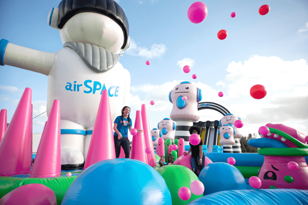 A giant bounce house with tall inflatable astronauts and huge bouncy balls flowing around. 