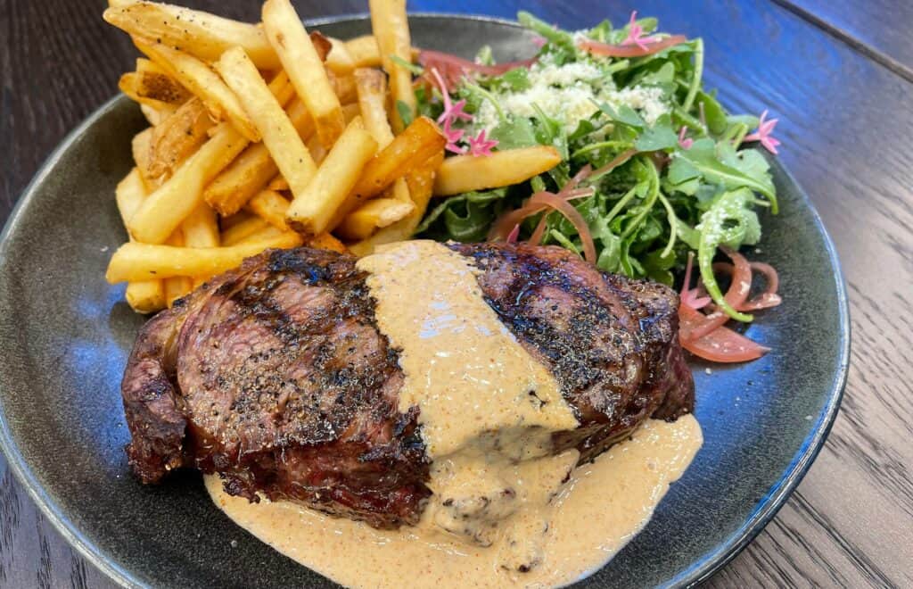 steak on a plate with fries and a salad