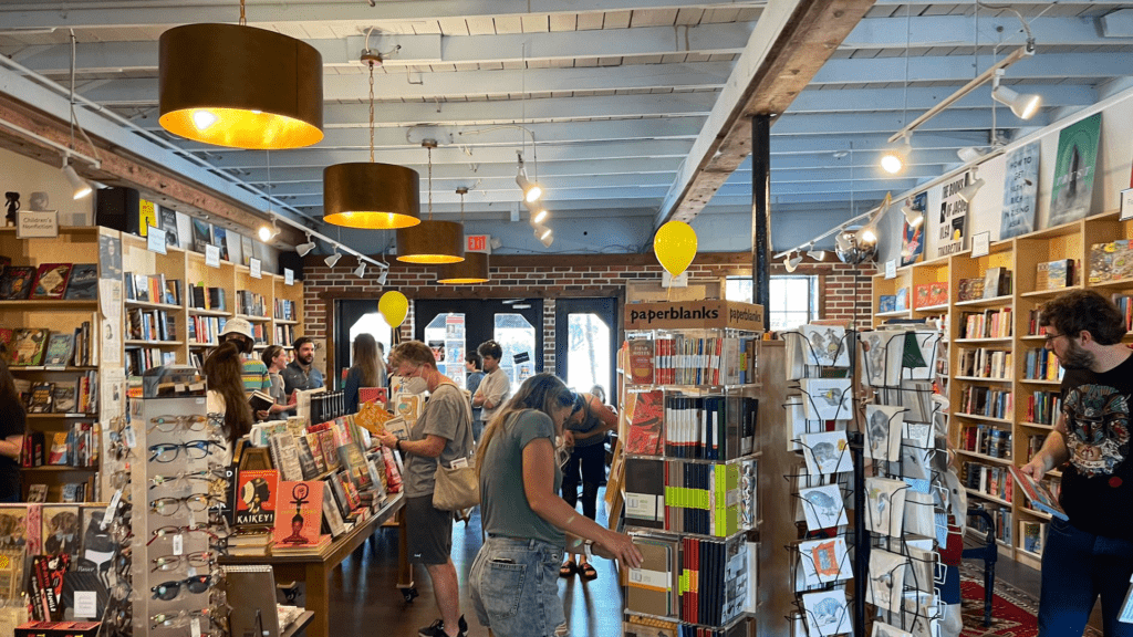 inside a small bookstore with people browsing through rows of books 